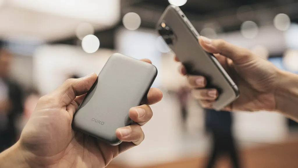 Main tenant un objet promotionnel avec un QR code visible dans un environnement lumineux de salon professionnel