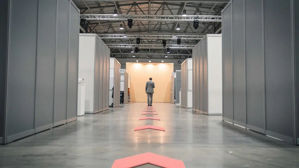 Allée de salon professionnel avec chevalets directionnels colorés guidant les visiteurs vers un stand en arrière-plan